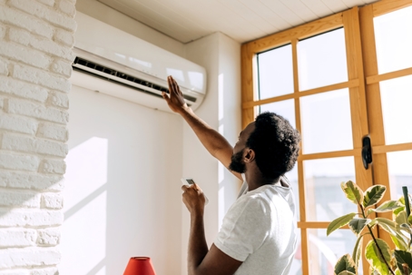 Man turning on air conditioner.